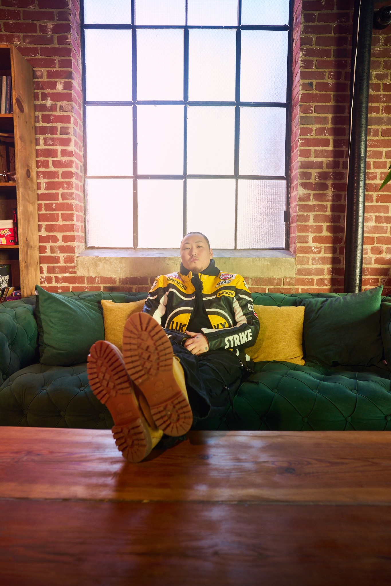 inSu relaxing on a green couch in a yellow and black motorcycle jacket