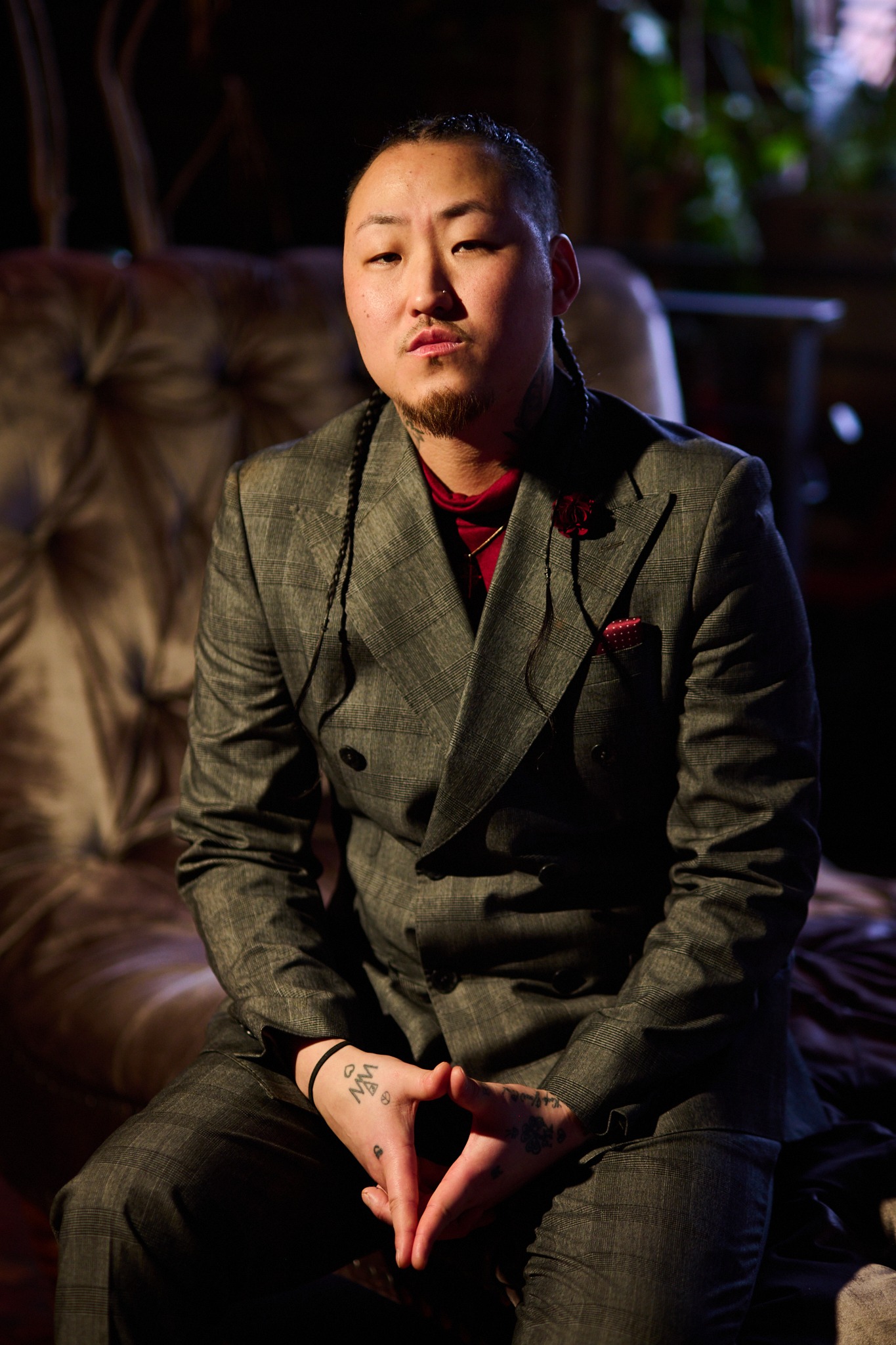 inSu in a grey double-breasted suit on leather seating