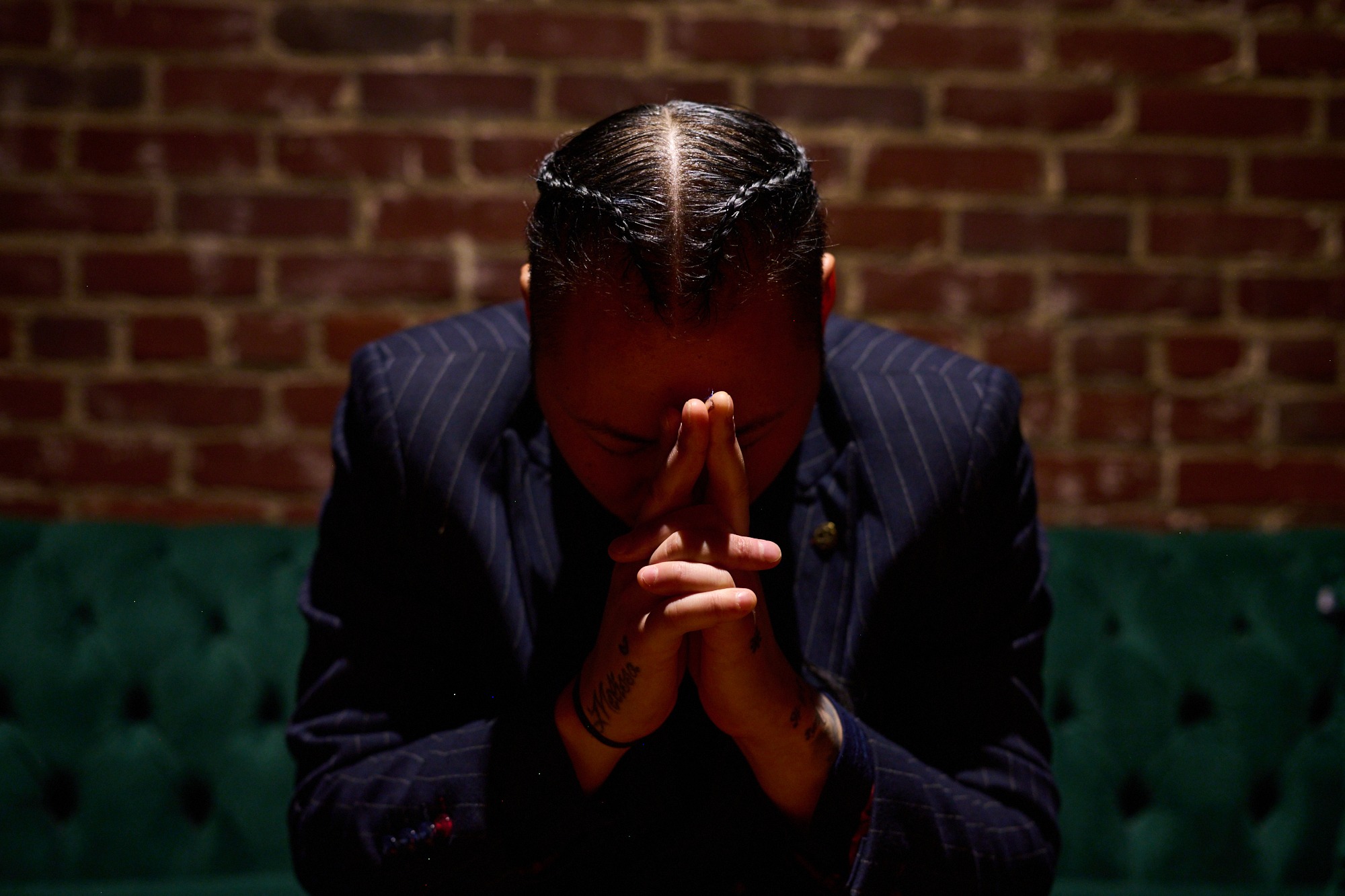 inSu in a pinstripe suit, head lowered and hands together